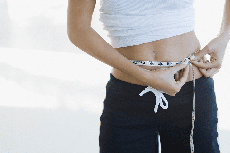 Woman measuring waist with tape measure
