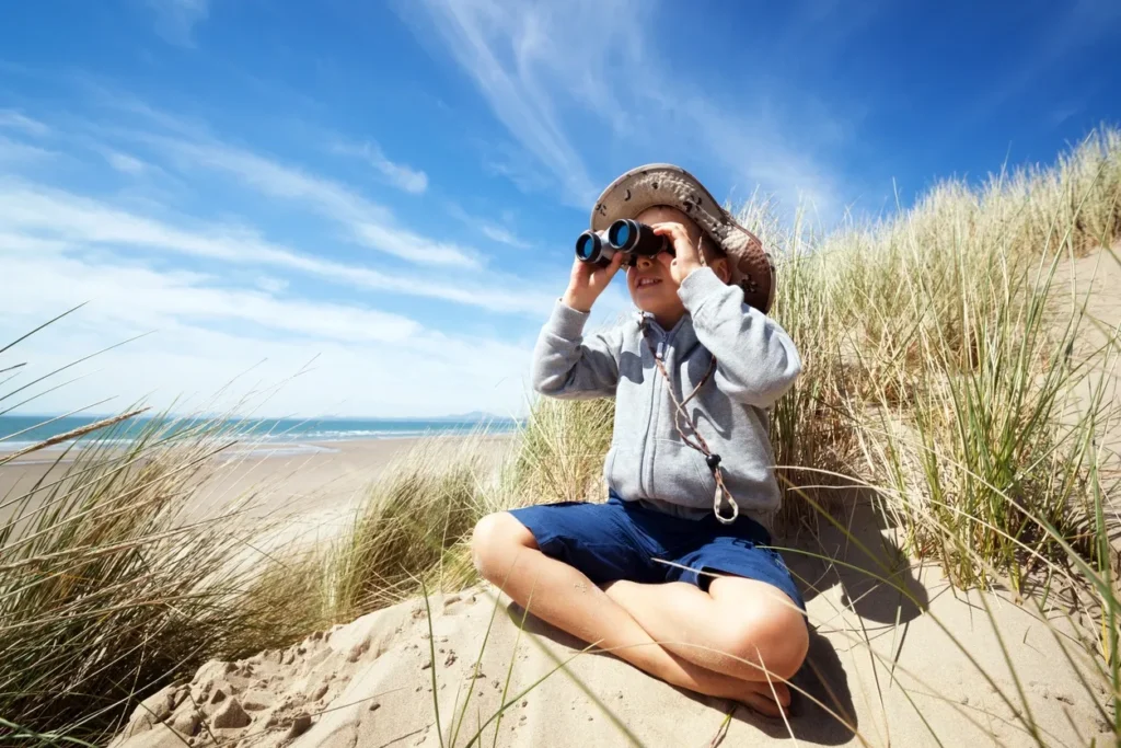 Kid sitting on beach with binoculars