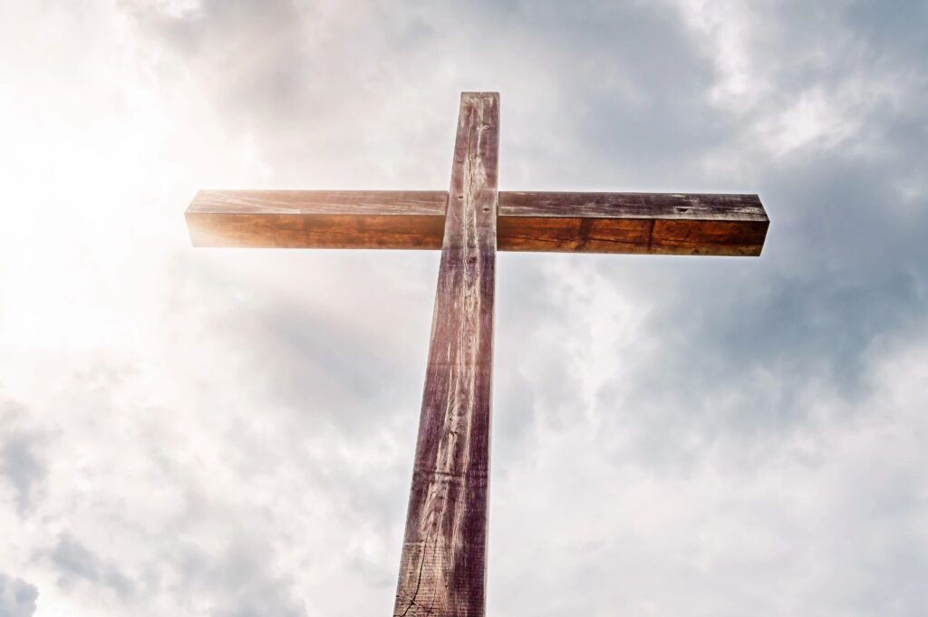 Wooden cross silhouetted against cloudy sky