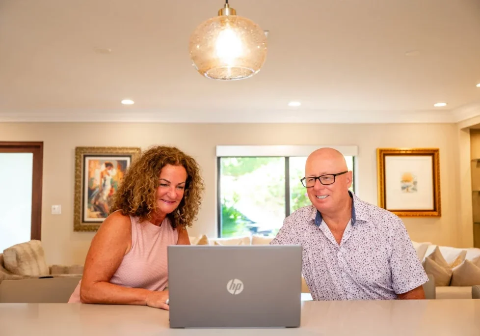 Smiling couple using laptop in cozy living room