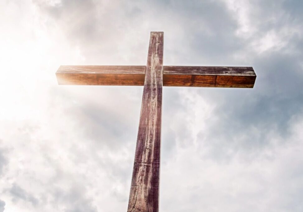 Wooden cross silhouetted against cloudy sky