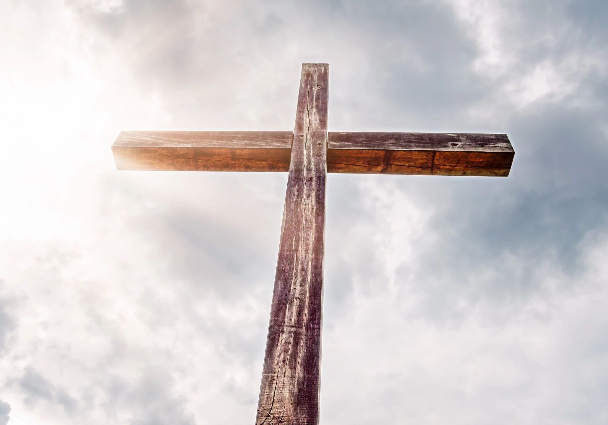 Wooden cross silhouetted against cloudy sky
